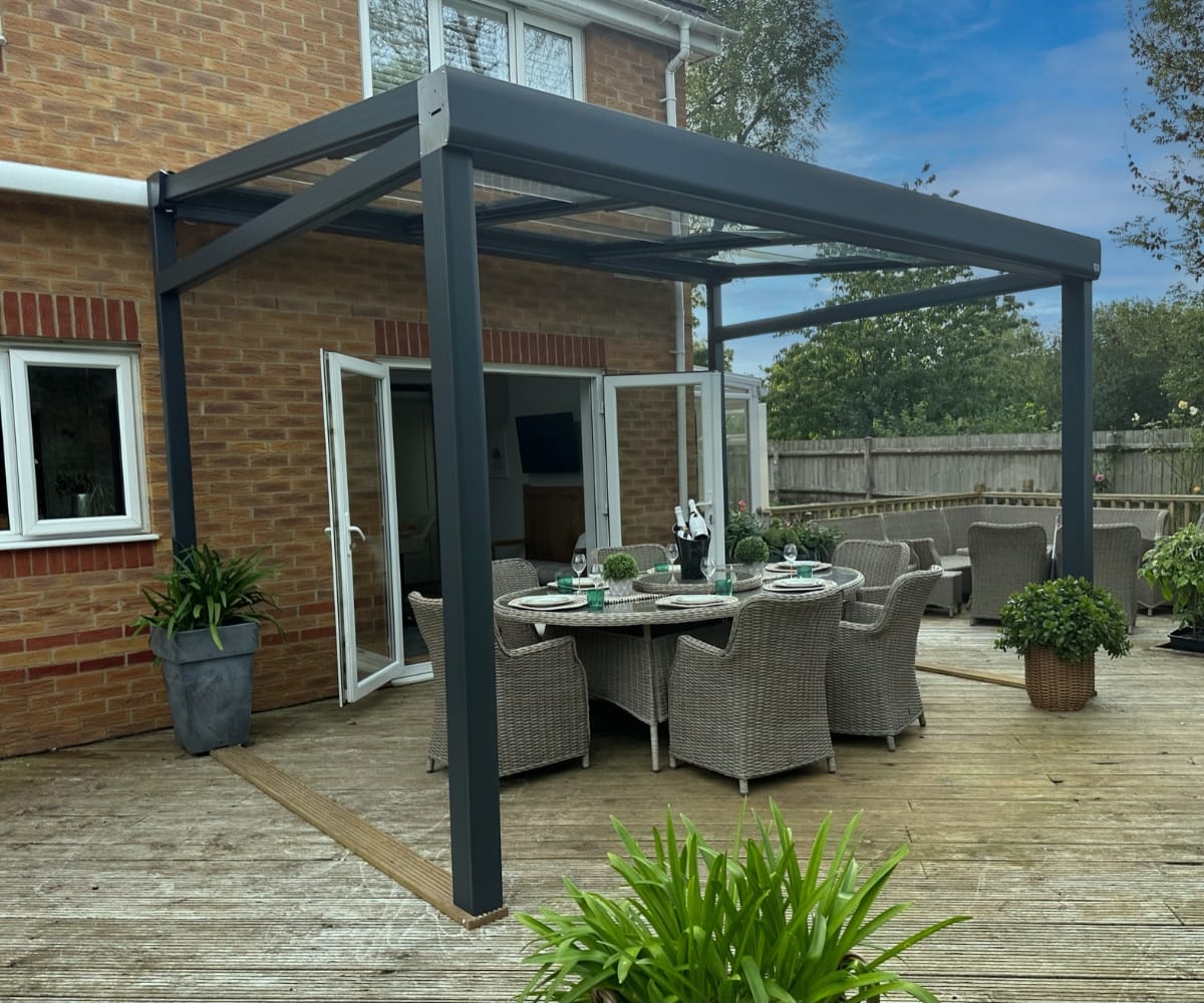 A VELARIUM retractable glass awning over a dining table in a luxurious garden