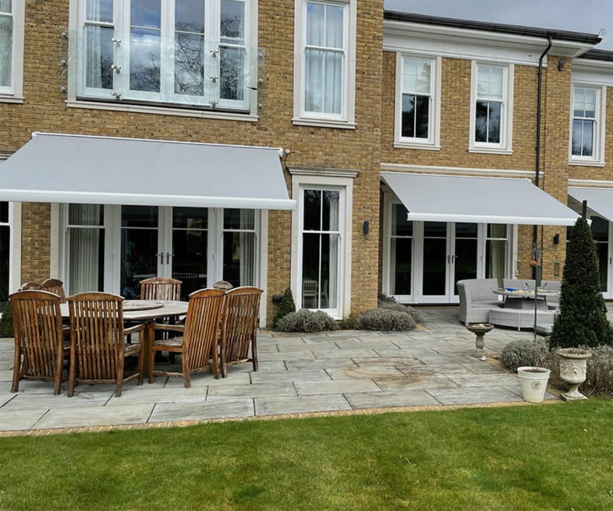 An awning on the outside of a house with tables and chairs, the awning was fitted by Great British Awning and Blind Company TM