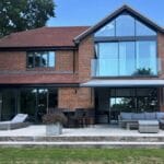 Modern brick house with large patio and retractable awning, designed to create a weatherproof home office space.
