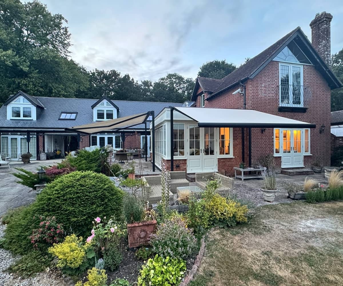 Traditional brick home with conservatory and extended weatherproof awning, offering a flexible outdoor working space.