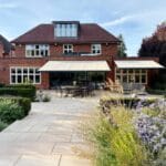 awning or glass veranda: Brick house with landscaped garden and multiple fitted awnings creating shaded outdoor seating