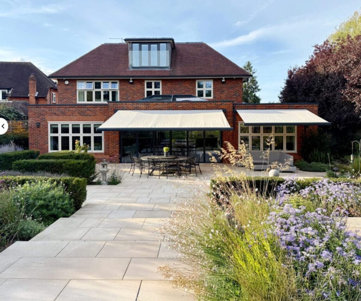 awning or glass veranda: Brick house with landscaped garden and multiple fitted awnings creating shaded outdoor seating