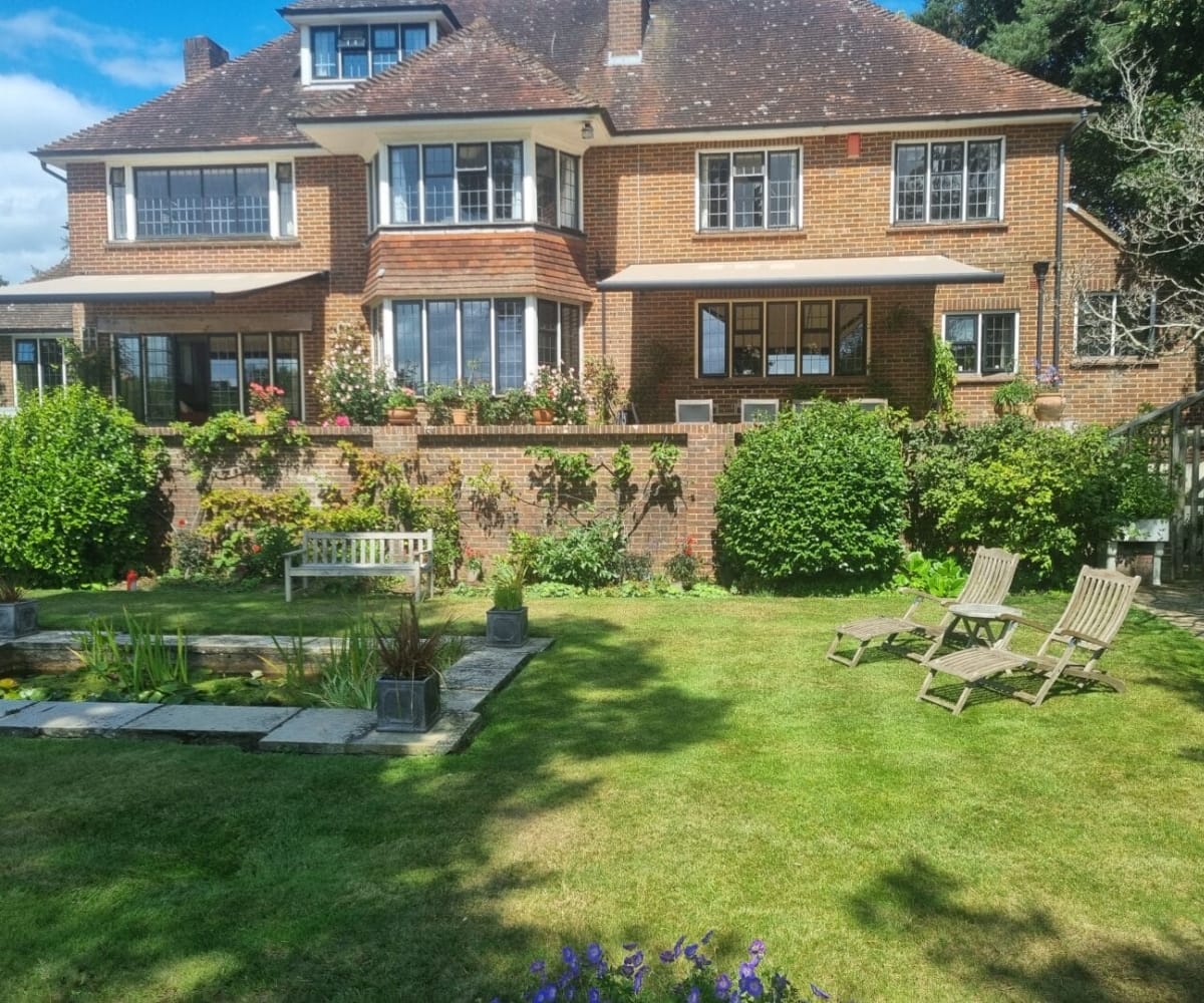 awnings and verandas garden inspiration: Traditional brick house with a mature garden and awning creating a relaxed outdoor seating area