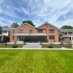 European-style garden awnings: Modern brick home with a landscaped garden and a minimalist awning providing shaded outdoor space