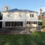 seasonal awnings: Rear view of a detached house with two extended awnings providing shade across a stepped patio and garden area.